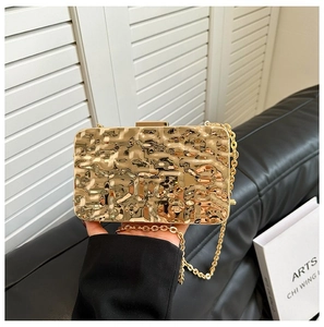 Close-up of golden evening clutch bag featuring metallic pleated texture and chain strap