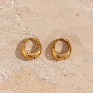 Macro view of polished 18K gold plated stainless steel teardrop earrings on stone