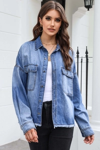 Detail of blue denim shirt with metal buttons, flap pockets and frayed fringe hemline