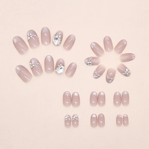 Close-up of nude pink cat-eye press-on nails with 3D rhinestones and pearl accents