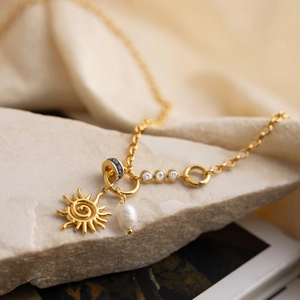Dettaglio di una collana placcata oro 18K con ciondolo a sole e perla d'acqua dolce bianca