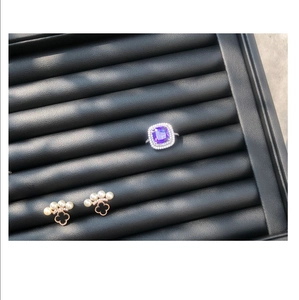 Détail de bague violette et boucles d'oreilles trèfle noir sur plateau de présentation