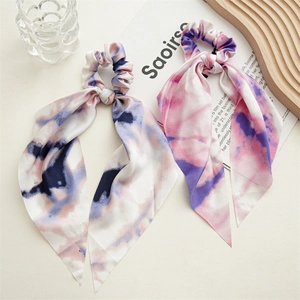 Detailed shot of tie-dye silk scrunchies with long ribbons on a decorative wooden tray