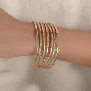 Gros plan de bracelets spirales dorés aux textures variées sur un fond en fourrure beige