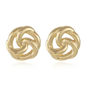 Detailed close-up of golden geometric twisted knot earrings with a high-polished finish
