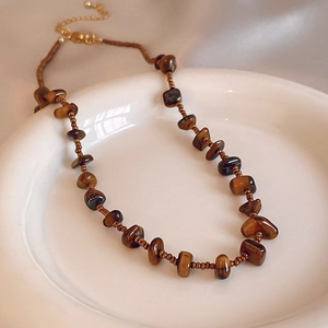 Dettaglio macro di perle occhio di tigre e perline di bronzo su una collana vintage