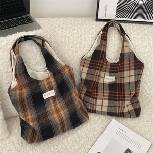 Dettaglio della borsa tote in lana scozzese su sfondo di morbido pile bianco