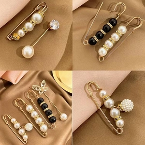 Set of minimalist gold geometric brooches with pearls and rhinestones on silk background