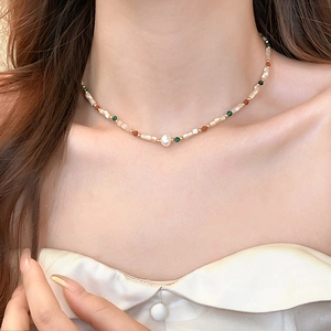 Close-up of a colorful beaded necklace with irregular baroque pearl on a woman's collarbone