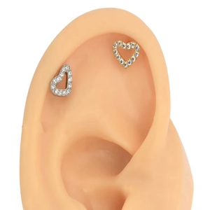 Macro view of heart-shaped G23 titanium studs with crystal inlay on a model ear