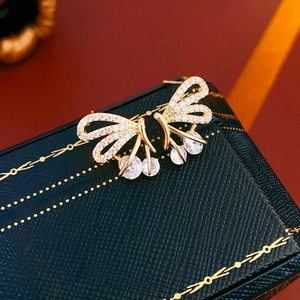 Detailed shot of gold butterfly earrings with zircon on a green jewelry box