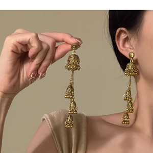 Close-up of vintage golden jhumka tassel earrings with intricate filigree bell details