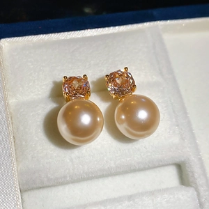 Detail of champagne gold pearl stud earrings with zircon inlay in a white jewelry box