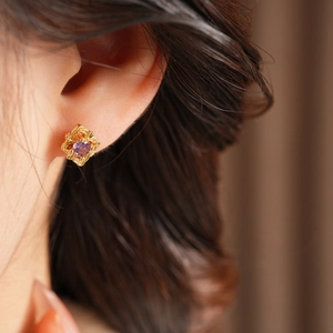 Macro shot of vintage floral earring with gold plating and a purple zircon center