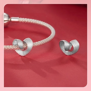 Macro shot of S925 silver heart charms with ribbon texture on a mesh chain bracelet