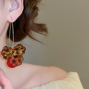 Detailed view of amber resin flower earrings with red pearls on a female model