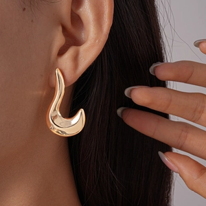 Detailed close-up of large irregular golden streamline stud earring on a model face