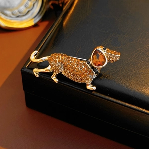 Macro shot of a golden dachshund brooch with amber rhinestones on a black leather box