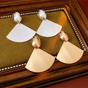Detail of gold and silver brushed metal fan earrings on vintage green jewelry tray