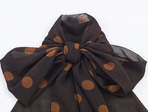 Detail of dark brown polka dot chiffon fabric tied in a bow with light texture