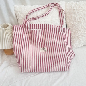 Macro detail of red and white striped canvas tote bag with front pocket and fabric label