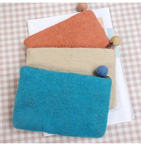 Close-up of handmade wool felt coin purses with dandelion pattern and pom-pom zippers