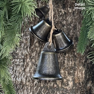 Close-up of vintage bronze metal bells with rustic texture and brown jute rope hanging