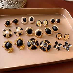 Macro shot of vintage black enamel and gold earrings with pearls on a golden tray