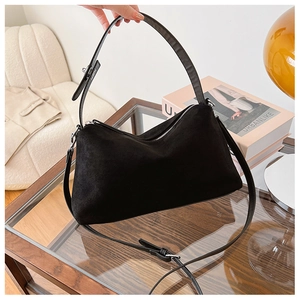 Detail of vintage black suede shoulder bag with adjustable strap and silver buckle hardware