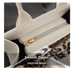 Close-up of white leather tote bag featuring a smooth metal zipper and leopard print lining