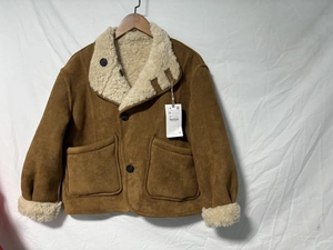Détail d'une veste en daim marron avec col en peau de mouton et grandes poches