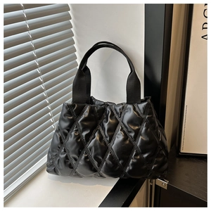 Detailed close-up of a black quilted tote bag with glossy finish and ribbon handles