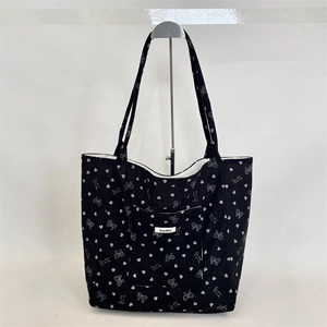 Detail of black corduroy tote bag with white bow patterns and large front pocket