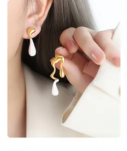 Detail of liquid gold streamlined drop earrings with white drip resin on model