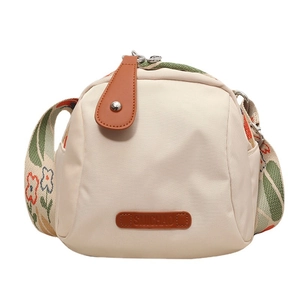 Beige canvas crossbody shell bag with floral strap and brown leather accents