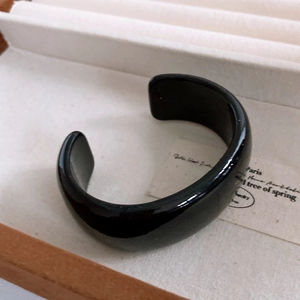 Detailed view of wide black resin cuff bracelet with high-polish finish in beige jewelry box