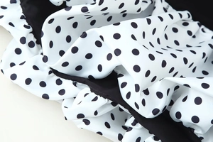 Macro detail of black and white polka dot pattern and ruched fabric texture on the dress