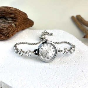 Detail view of silver quartz bracelet watch with rhinestones on a white marble surface