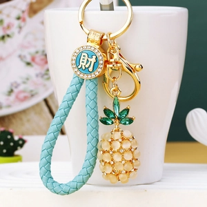 Detailed view of opal pineapple keychain with blue woven strap and golden fortune charm