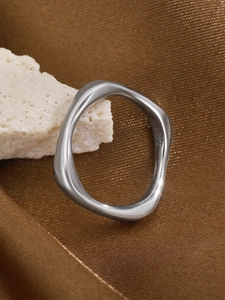 Detailed macro view of irregular wavy silver steel ring on textured stone and silk background