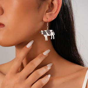 Close-up of model wearing black and white cow print heart earrings in a minimalist style