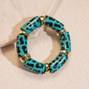 Detailed shot of teal leopard print tube beads and gold spacers on an elastic bracelet