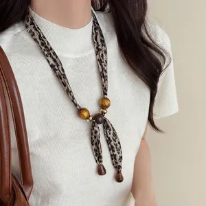 Detail of leopard print silk scarf necklace with resin beads and metallic accents