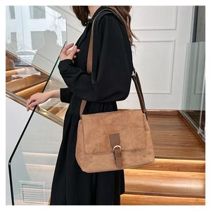 Brown faux suede tote bag featuring dark leather strap and buckle on a model