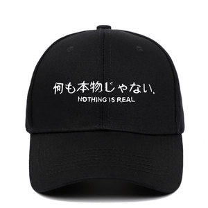 Detail der weißen Nothing Is Real Stickerei auf einer schwarzen Baumwoll-Basecap