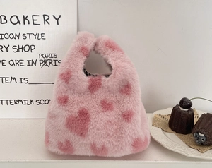 Détail du sac à main en peluche rose à cœurs avec une doublure à carreaux noirs et blancs