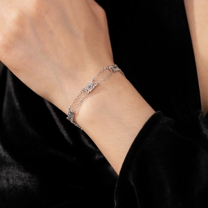 Detail of silver hollow flower square bracelet on wrist against black velvet background