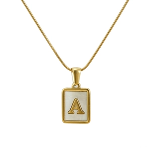 Détail du collier en or avec la lettre A embossée sur un pendentif en nacre blanche