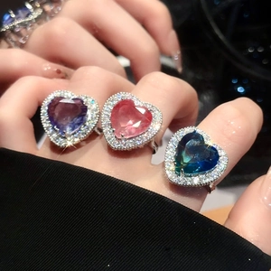 Detailed view of heart-shaped zircon rings in purple, pink and teal on a silver band