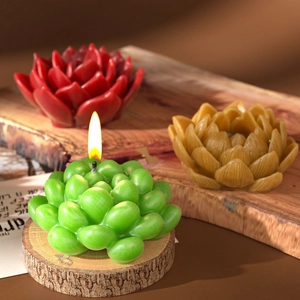 Three realistic succulent shaped candles in green, red and yellow on a wooden surface